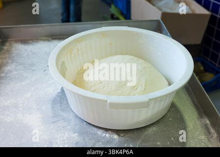 Frischer Brotteig, der in einer weißen Schüssel zum Backen steht Stockfoto