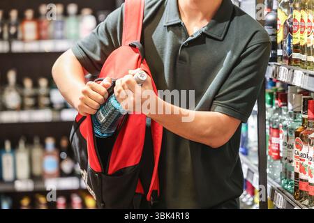Köln, Deutschland. Juni 2025. ILLUSTRATION - Ein Mann legt eine Flasche alkoholischen Getränks in seinen Rucksack in einem Supermarkt. Eine EHI-Studie über Ladendiebstahl und Bestandsabweichungen wird veröffentlicht. Quelle: Oliver Berg/dpa/Alamy Live News Stockfoto