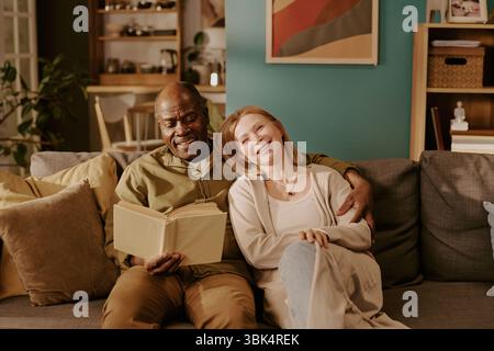 Seniorenpaar, das sich auf dem Sofa entspannt und zu Hause lächelt Stockfoto