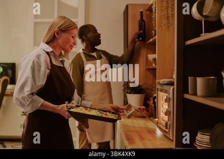 Senior Kaukasierin und Senior Schwarzer Mann bereiten gemeinsam Abendessen in der Küche vor Stockfoto