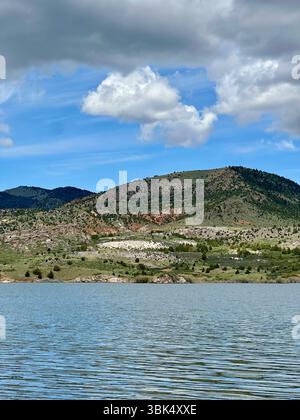 Sträucher, die teilweise in einen ruhigen Bergsee getaucht sind, vor einer Kulisse aus sanften Hügeln und dramatischen Wolken. Die Hochwüste liegt in Kap. Stockfoto