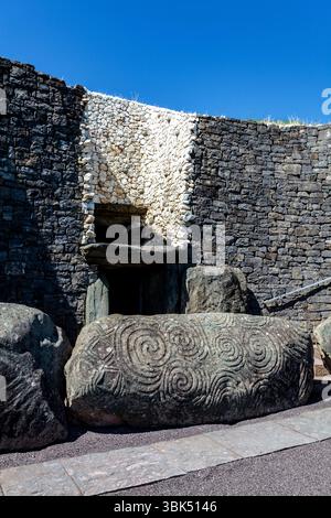 Newgrange, ein neolithisches Passage-Grab mit weißem Quarz und hoch verzierten Bordsteinen: Der HauptBordstein mit Triskelion auf der linken Seite Stockfoto