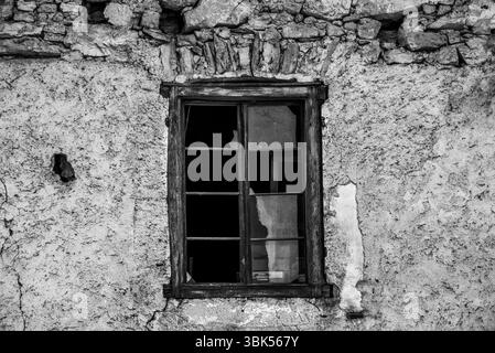 Altes Holzfenster mit Glasscherben und alter abblätternder Wand aus der Zeit in Fondo, Valle di Non in Trient, Italien Stockfoto