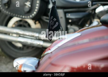 Das Heck des Custom Cruiser-Motorrads zeigt eine schwarze Flagge des Viking MC Bulgarien über einem metallisch roten Tank, zwei Chrom-Auspuffrohre und ein verschwommenes Rad mit Stockfoto