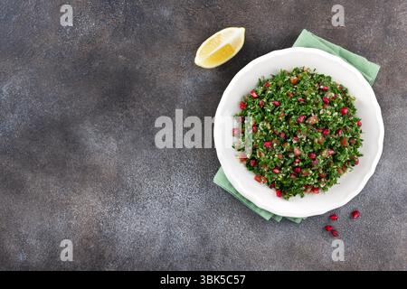 Veganer vegetarischer Salat mit Quinoa, Tomaten, Granatapfel, Petersilie, Zitrone und Dressing. Makro. Tabbouleh-Salat. Stockfoto