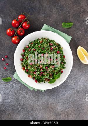 Veganer vegetarischer Salat mit Quinoa, Tomaten, Granatapfel, Petersilie, Zitrone und Dressing. Makro. Tabbouleh-Salat. Stockfoto