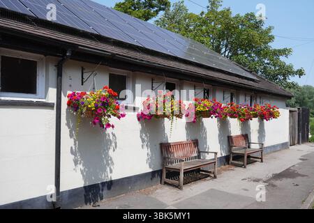 Äußere des traditionellen englischen Pubs mit hängenden Blumenkörben zur Dekoration. Malerisches Wirtshaus im Dorf Stockfoto