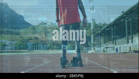 Stehender männlicher Sportler im Teenageralter mit rotem Oberteil, Prothesenklingen auf rotem Track mit Startblöcken Stockfoto