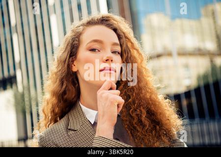 Selbstbewusste Geschäftsfrau, die draußen steht und im Hintergrund ein Stadtbild reflektiert, das professionellen Charme ausstrahlt Stockfoto