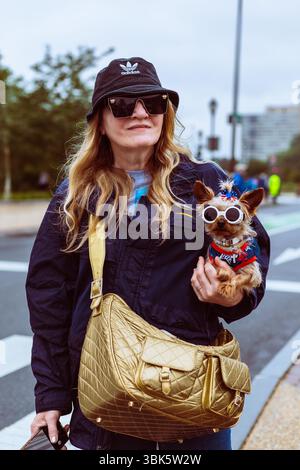 Frau hält ihren kleinen Hund in amerikanischem Patriotenkostüm und Sonnenbrille während des No Kings Protests in Philadelphia, PA am 14. Juni 2025. Stockfoto