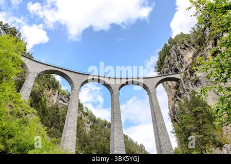 Das historische Landwasser-Viadukt überspannt ein malerisches Tal unter klarem blauen Himmel in den Schweizer Alpen Stockfoto