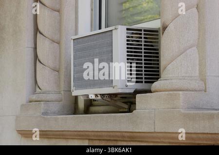 Außenansicht der Klimaanlagen-Fenstereinheit, die von der Fensterbank mit einer darunter montierten tragbaren Sicherheitsvorsatzstütze extrudiert wird, mit elegant, DE Stockfoto