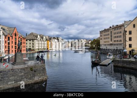 Eine friedliche Uferszene mit lebhaften Gebäuden, ruhigem Wasser und verschiedenen Booten unter einem dramatischen bewölkten Himmel, die an eine ruhige Küstenambiank erinnern Stockfoto