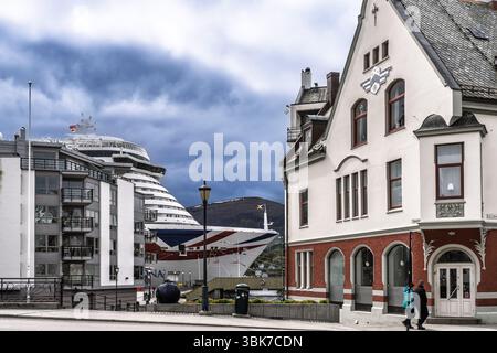 Malerischer Blick auf die Stadt mit charakteristischen architektonischen Gebäuden entlang einer Uferpromenade, mit einem großen Kreuzfahrtschiff im Hintergrund unter einem bewölkten Himmel, Reres Stockfoto