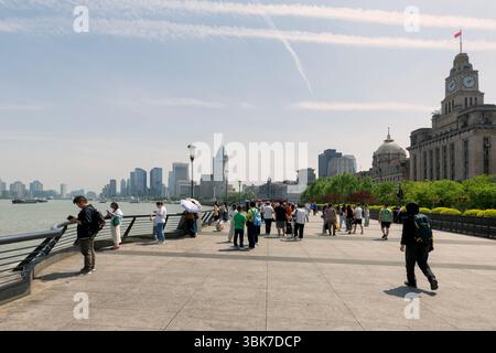 Shanghai, China - 20. April 2025: Fußgänger schlendern entlang des Bund, einer berühmten Uferpromenade, die von Gebäuden aus der Kolonialzeit wie dem HIS gesäumt ist Stockfoto
