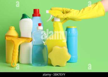 Hand des Hausmeisters und Reinigungsmittel auf grünem Hintergrund Stockfoto