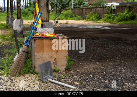 Besen und eine Schaufel stehen auf dem Boden neben einer Holzkiste. Die Szene ist etwas chaotisch und ungepflegt Stockfoto