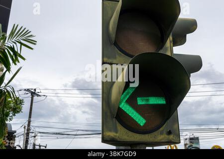 Bali, Indonesien - 25. Dezember 2024: Eine Ampel mit einem grünen Pfeil leuchtet auf, um anzuzeigen, dass die Fahrer nach links abbiegen sollten. Stockfoto