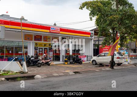 Bali, Indonesien - 25. Dezember 2024: Alfamart Supermarkt mit einem weißen Auto davor. Stockfoto