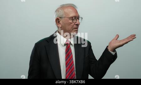 Senior Mann im Business-Anzug, der mit der Hand geöffnete Gesten zeigt, isoliertes Konzept auf weißem Hintergrund. Stockfoto