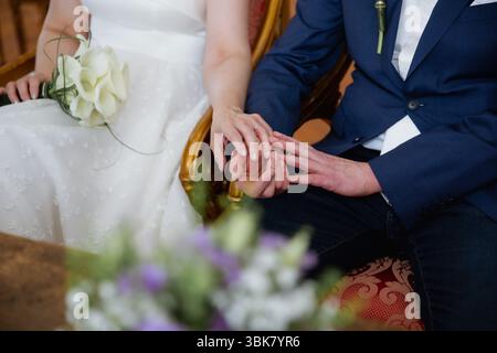 Nahaufnahme von Braut und Bräutigam, die Hände halten, zusammen sitzen, Hochzeitstag-Konzept Stockfoto