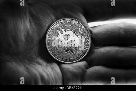 Physisches Bitcoin in Händen, Nahaufnahme Foto in Schwarzweiß Stockfoto
