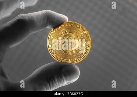 Physische Bitcoin in den Händen gehalten Nahaufnahme Foto in selektiven Farben Stockfoto