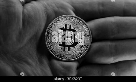 Physisches Bitcoin in Händen, Nahaufnahme Foto in Schwarzweiß Stockfoto