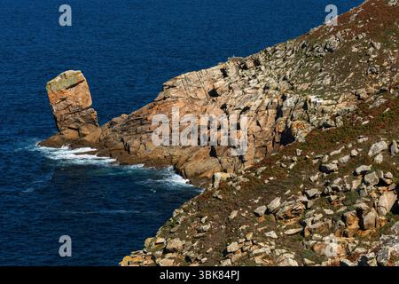 Ein zeitvernarbener, geneigter Nadelfelsen scheint von der Spitze eines der zerklüfteten Granitvorsprünge der Pointe du Raz in Finistère, Bretagne, Frankreich, in den Atlantik zu stürzen, einem der westlichsten Punkte des französischen Festlandes. Die spektakuläre Halbinsel ist eine der großen Sehenswürdigkeiten Frankreichs, bekannt für ihre unberührte natürliche Schönheit. Stockfoto