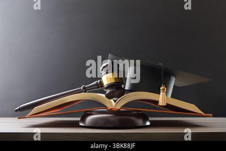 Erziehungsurteilskonzept mit offenem Buch mit Mörtelplatte und Keule oben auf Holzsockel auf einem Tisch und schwarzem isoliertem Hintergrund. Vorderansicht. Stockfoto