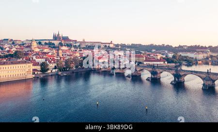 Wenn die Dämmerung über Prag bricht, erleuchten die goldenen Farbtöne die mittelalterliche Architektur entlang der Moldau, mit Blick auf die berühmte Karlsbrücke und das Schloss Hradcany, was ein atemberaubendes Panorama schafft. Stockfoto