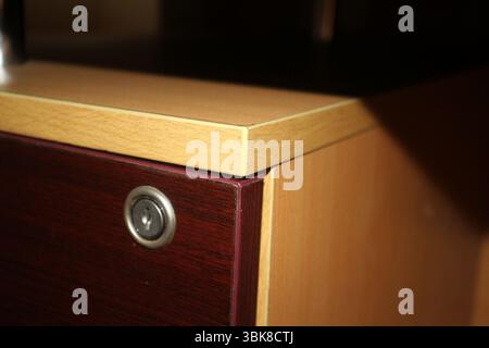 Nahansicht einer hölzernen Schubladenecke mit integriertem Metallschloss. Die Schublade verfügt über eine satte, dunkle Oberfläche auf der Vorderseite. Stockfoto