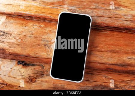 Ein modernes Smartphone mit einem leeren schwarzen Bildschirm liegt schräg auf einer rustikalen Holzoberfläche Stockfoto