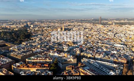 Aus der Vogelperspektive auf eine weitläufige Stadtlandschaft mit historischer Architektur, mit einer prominenten Kathedrale und modernen Gebäuden, unter einem klaren blauen Himmel. Stockfoto