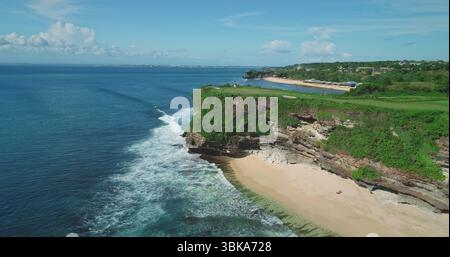 Atemberaubender Blick aus der Vogelperspektive auf Pantai Dreamland Beach in Bali, Indonesien, mit türkisfarbenem Wasser, weißem Sand, üppigen Klippen, und rauschende Wellen in einem tropischen Paradies Stockfoto