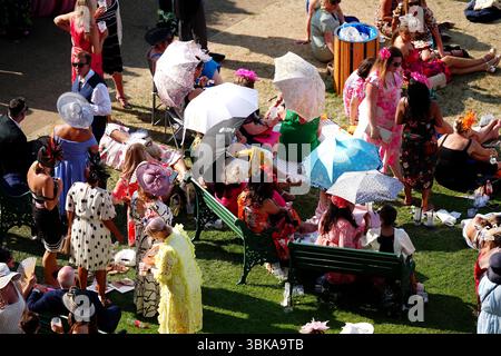 Racegoers schützen sich am dritten Tag von Royal Ascot auf der Ascot Racecourse, Berkshire, vor dem warmen Wetter unter Sonnenschirmen. Bilddatum: Donnerstag, 19. Juni 2025. Stockfoto
