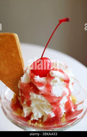 Nahaufnahme der Maraschino-Kirsche mit Erdbeer-Eiscreme und Sundae-Schlagsahne Stockfoto