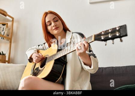 In einem gemütlichen Wohnzimmer schnallt eine junge Frau freudig ihre Gitarre, um Kreativität zu genießen. Stockfoto