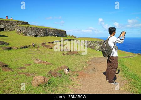 Reisende besuchen das Orongo Village mit einer Gruppe von Steinhäusern, Ruinen, ein Zeremonialzentrum auf der Osterinsel, Chile, Südamerika Stockfoto