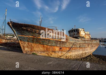 Verwittertes und rostiges Fischerboot Schiffswrack am sillon des Hafens in Camaret-sur-Mer, Bretagne, unter klarem blauem Himmel. Stockfoto