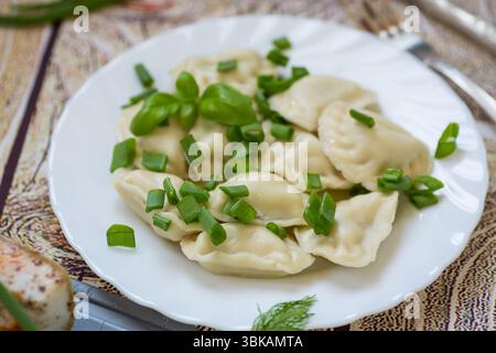 Heiße Klöße auf einem Teller mit Zwiebeln auf dunklem Hintergrund. Stockfoto