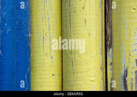 Gelb und blau lackierte Holzhölzer einer alten Holzhütte Stockfoto