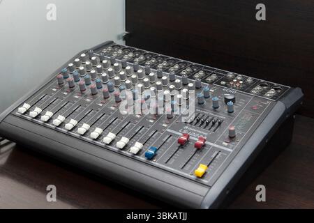 CHISINAU, MOLDAWIEN - 14. MÄRZ 2025; Audio-Mischpult mit verschiedenen Knöpfen und Schiebern in realistischem Stil auf dunkler Holzoberfläche, represen Stockfoto