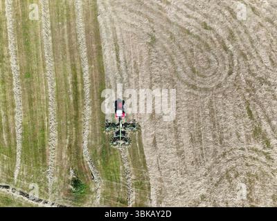 Ein Traktor mit einem heuschneider auf dem Feld, erschossen mit einer Drohne Stockfoto