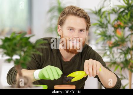 Ein lächelnder Mann, der zu Hause mit Pflanzen arbeitet Stockfoto