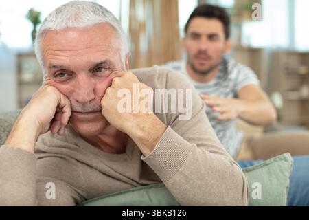 Vater, der seinen Sohn verpönt, saß auf einer Couch Stockfoto