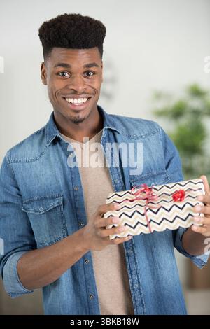 Aufgeregter Mann, der ein Geschenk in Geschenkverpackung hält Stockfoto