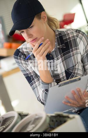 Arbeitnehmerin, die am Zentralheizungskessel arbeitet Stockfoto