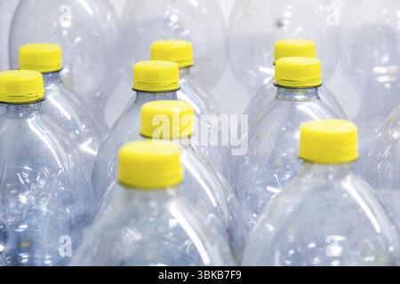Eine Sammlung transparenter Kunststoffflaschen mit gelben Schraubverschlüssen Stockfoto