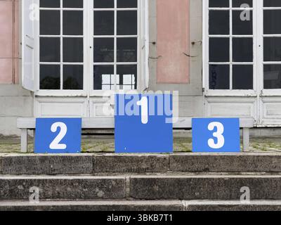 Ein Siegerpodest mit den nummerierten Plätzen 1, 2 und 3, auf einer Steintreppe vor einem Gebäude mit großen weißen Doppelfenstern in Duesseldo Stockfoto